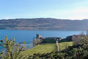 a castle on a hill next to a body of water at Herons Rest in Drumnadrochit