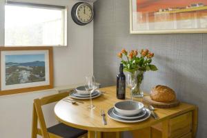 uma mesa com pratos e um vaso de flores e um relógio em Herons Rest em Drumnadrochit