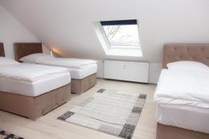 - une chambre mansardée avec 2 lits et une fenêtre dans l'établissement T&K Apartments near Messe Fair Trade Düsseldorf und Airport 3B, à Duisbourg