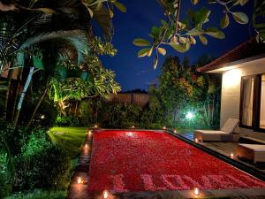 a garden with a red rug in front of a house at The Sawah Resort & Villa in Ubud