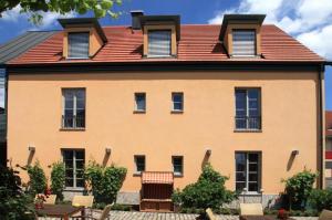een groot geel huis met een rood dak bij Hotel Weinblatt in Sommerach