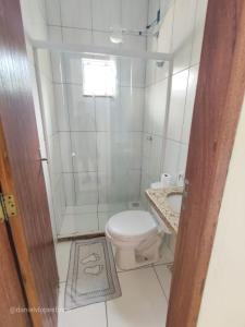 ein weißes Bad mit einem WC und einer Dusche in der Unterkunft Cantinho da Vitória em Conceição de Jacareí in Mangaratiba