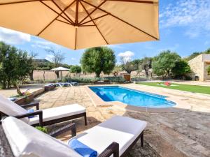 a pool with an umbrella and chairs and a table and a pool at Holiday Home Son Tey by Interhome in Sineu