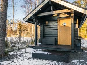 uma casa de banho de madeira com uma porta de madeira na neve em Holiday Home Hukka 6 by Interhome em Harkala