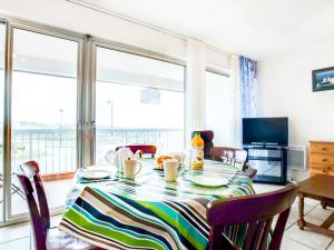 een eettafel met stoelen en een groot raam bij Apartment Port Maria-1 by Interhome in Quiberon