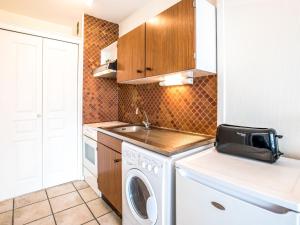 een kleine keuken met een wasmachine en een wastafel bij Apartment Port Maria-1 by Interhome in Quiberon