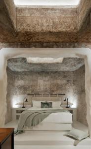 a bedroom with a large bed with a stone wall at Winery Hotel 1870 in Fira