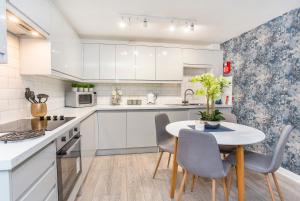 a kitchen with white cabinets and a table and chairs at Minster's Reach York close to York Minster in York
