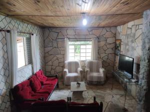 a living room with a red couch and a tv at Sítio Felicidade-Capitolio-Furnas-MG in Elisiário Lemos