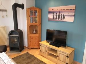 een woonkamer met een tv en een fornuis bij Strandläufer in Reitland