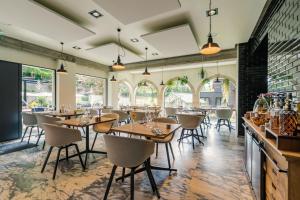 Un restaurante con mesas y sillas de madera y ventanas. en Hostellerie du Grünewald, en Luxemburgo