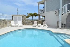 una piscina con 2 sillas y una casa en Princess Mahault - Beachfront - Orient bay - luxury apartment en Orient Bay