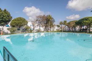 una gran piscina azul con árboles y edificios en Apartamento Almadraba, en Chiclana de la Frontera