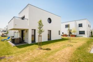 een wit huis met een tuin met twee bomen bij Les Cottages d'ANADARA in Anglet