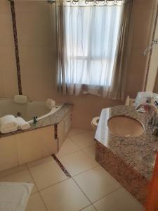 uma casa de banho com um lavatório, uma banheira e um WC. em San Marino Palace Hotel em Guarapuava