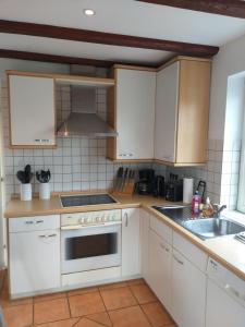 een keuken met witte kasten en een fornuis met oven bij Strandläufer in Reitland