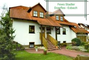 une grande maison blanche avec un toit rouge dans l'établissement Stadler Ferienwohnung, à Neudörfles