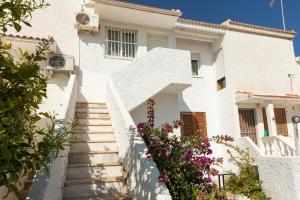 una casa blanca con escaleras y flores en Bungalow cerca de la playa de La Mata, en Torrevieja