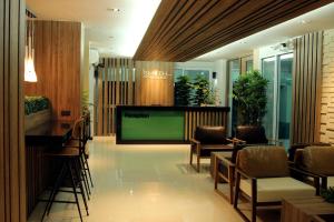 a lobby with a television and chairs and a bar at Smith Residence in Suratthani