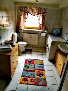 La salle de bains est pourvue d'un lavabo, de toilettes et d'un tapis. dans l'établissement Stadler Ferienwohnung, à Neudörfles