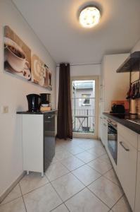 une cuisine avec des armoires blanches et un sol carrelé dans l'établissement Zum Augustiner I, Erfurt Zentrum, à Erfurt