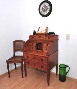 une commode avec une chaise et un réveil sur un mur dans l'établissement Zum Augustiner I, Erfurt Zentrum, à Erfurt
