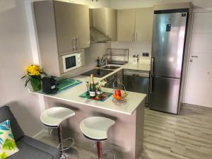 a kitchen with a counter with stools and a refrigerator at Turquesa 10 in La Pineda