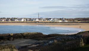 a beach with a group of people walking on the sand at Seacroft in Holyhead
