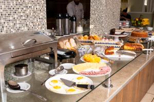 a buffet line with plates of food on a counter at Victoria Plaza Hotel in Palmas