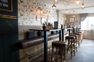 a bar with brown leather seats and a row of bar stools at Seacroft in Holyhead