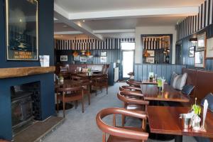 a restaurant with wooden tables and chairs and a fireplace at Seacroft in Holyhead