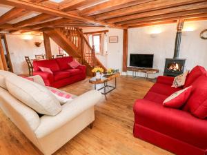 ein Wohnzimmer mit zwei roten Sofas und einem Kamin in der Unterkunft Cowslip Cottage in Haverfordwest