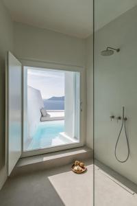 a bathroom with a glass window with a swimming pool at The Saint Hotel in Oia
