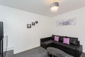 a living room with a black couch and pink pillows at Cherry Property - Plum Suite in Blackpool
