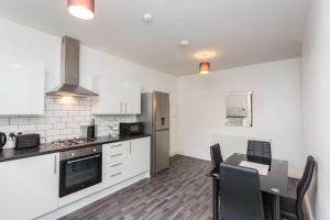 a kitchen with white cabinets and a table with chairs at Cherry Property - Plum Suite in Blackpool