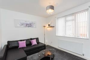 a living room with a black couch and pink pillows at Cherry Property - Plum Suite in Blackpool