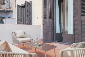 a patio with chairs and a table with a glass of wine at Sweet Inn - Sepulveda in Barcelona