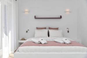 a white bedroom with a large bed with two pillows at Blue Amaryllis Villas in Santa Maria