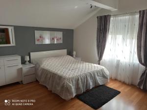 a bedroom with a white bed and a window at Apartments Roncevic in Zadar