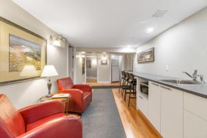 a living room with red chairs and a kitchen at Manoir de la Tour in Quebec City