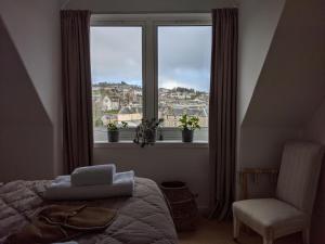 a bedroom with a bed and a chair and a window at Central Hawick spacious stylish flat with log burner in Hawick