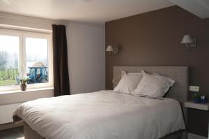 a bedroom with a large white bed with a window at B&B De Fruithoeve in Hoeselt