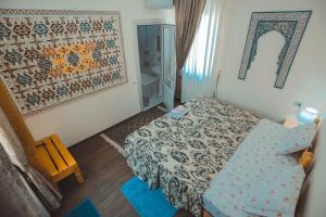 een kleine slaapkamer met een bed en een spiegel bij Yasmin in Bukhara