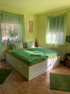 a bedroom with a large bed with a green comforter at Panni Vendégház in Egerszalók