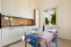una cocina con mesa con sillas azules y fregadero en Casina Farnarari by BarbarHouse, en Monteroni di Lecce