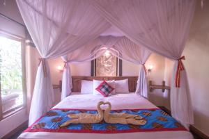 two animals laying on a bed in front of a window at Trijaya Guest House Pemuteran in Pemuteran