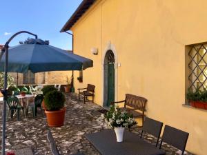 a patio with a table and a blue umbrella at La vecchia canonica in Fivizzano