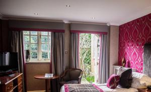 a hotel room with a bed and a window at Langshott Manor - Luxury Hotel Gatwick in Horley