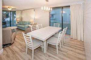 une salle à manger avec une table et des chaises blanches dans l'établissement White Caps 206, à Romar Beach