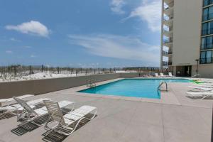 a swimming pool with lounge chairs next to a building at Wind Drift 408SW in Perdido Key +42 photos